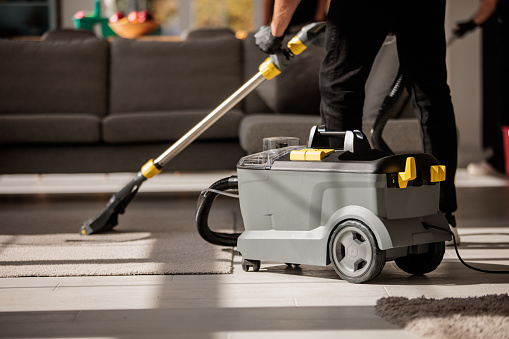 Professional carpet cleaning technician with equipment in a living room